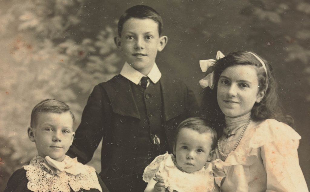 Old, sepia photograph of four children..