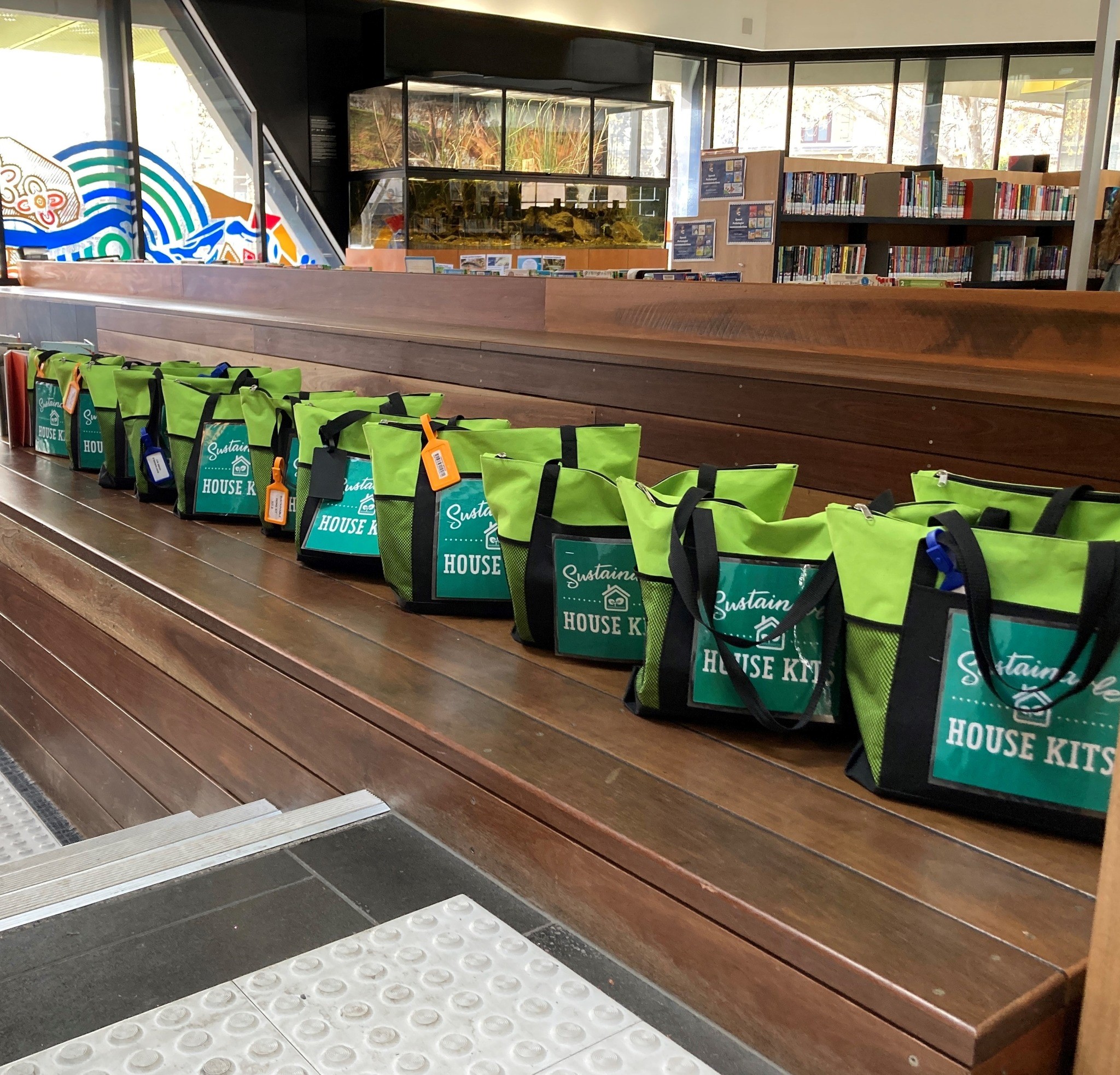 Green Sustainable House Kits lined up on a bench at Bendigo Library.