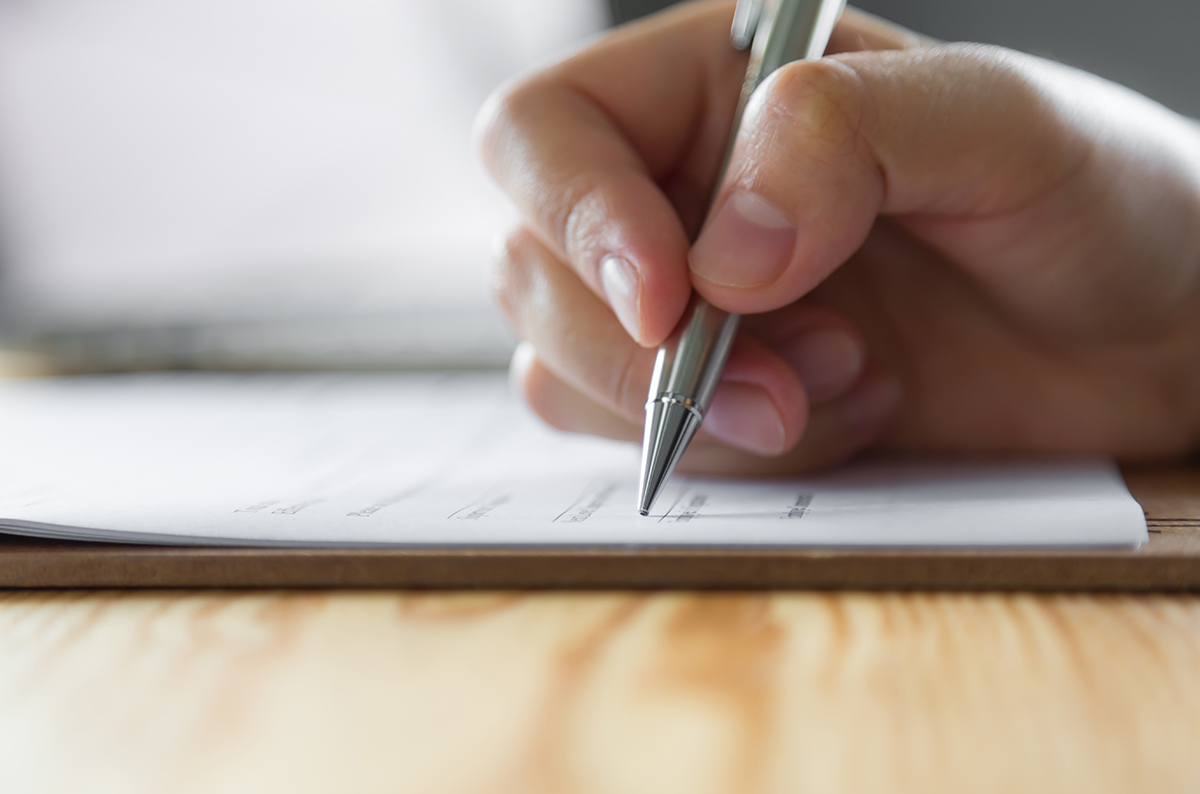 Hand holding pen over paper