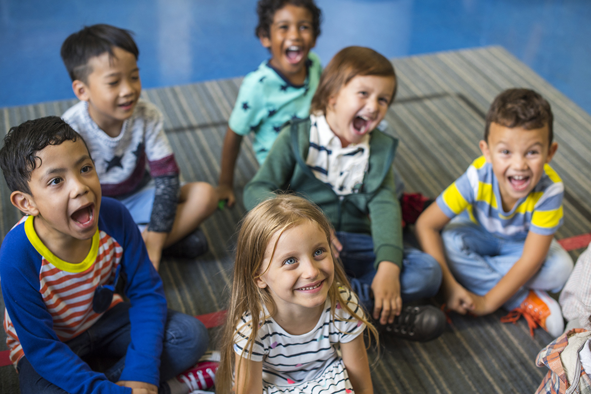 A group of happy, diverse children sit on the floor.