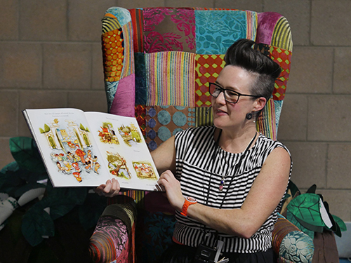 Woman reading children's book on colourful chair