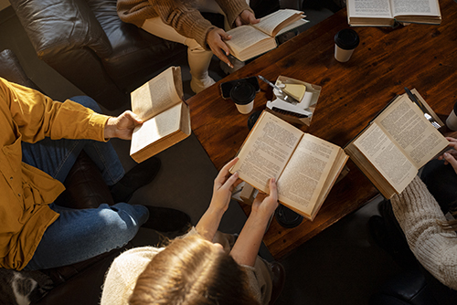 Group of people sitting around a table with books open.