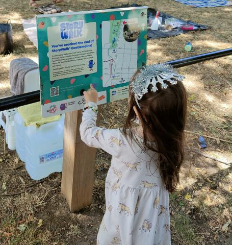 little girl standing in front of a StoryWalk board.